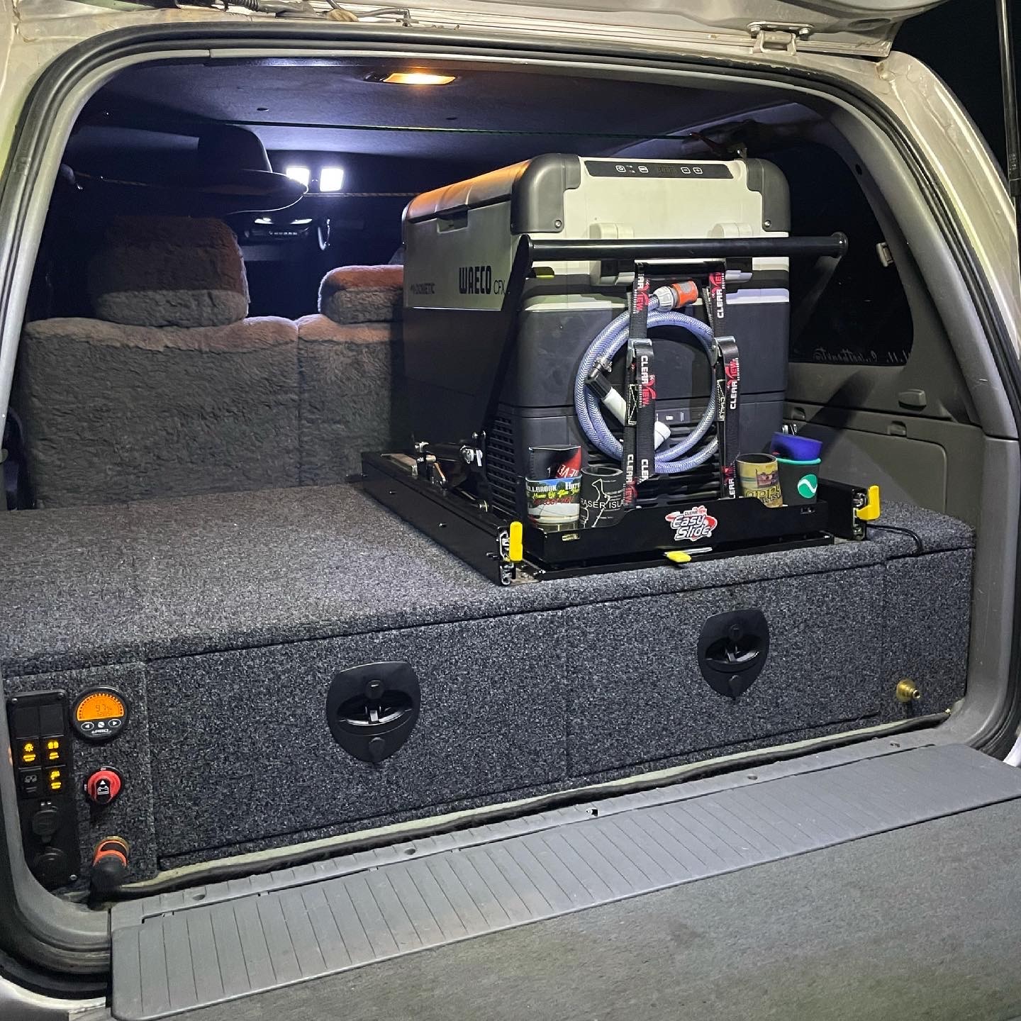 Fridge mounted on a drawer system in the back of a 4WD with a lit switch panel